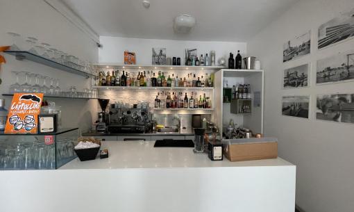 Bar moderno con scaffali di liquori e macchina da caffè.