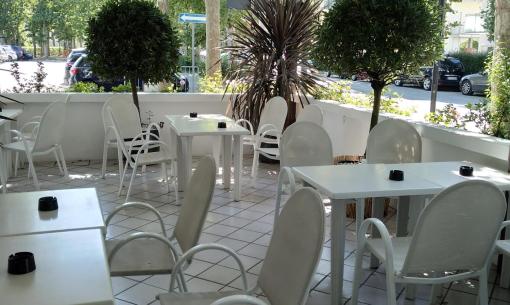 Freiluftcafé mit weißen Stühlen und Pflanzen.